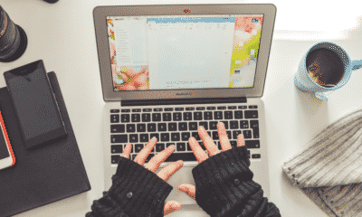 Overhead shot of woman typing on laptop with tea