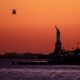 In this file photo taken on October 14, 2019 a helicopter flies past the Statue of Liberty as the sun sets in New York City