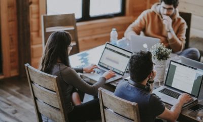 Three people using Macbooks at a table