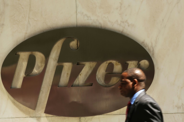 A man walks past the Pfizer logo on the drug maker's headquarters in New York