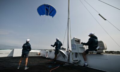 The startup Beyond The Sea tests a blue inflatable kite sail the size of a small studio to pull a specially-designed catamaran across the water