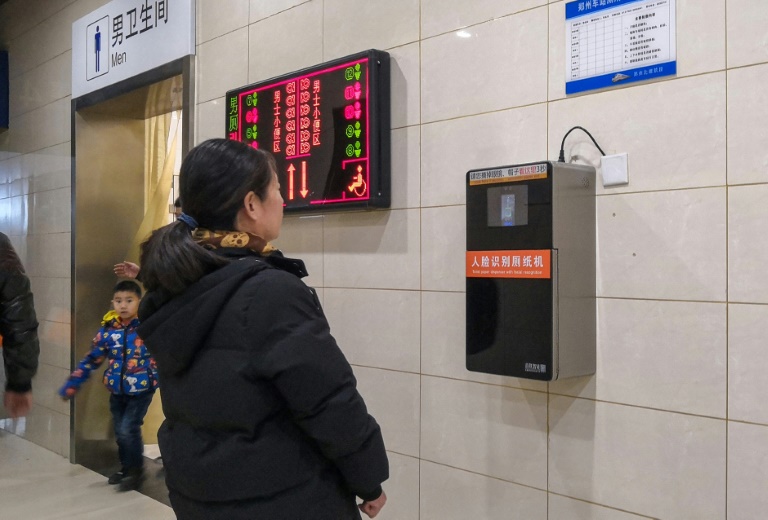 An automatic toilet paper dispenser (R) at a Chinese railway station uses facial recognition technology. China is drafting rules on use of the technology